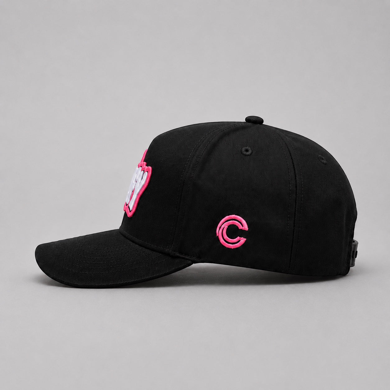 Right side view of the Capstify Skull Voltage black A-Frame baseball cap featuring a minimalist pink embroidered Capstify "C" logo on the side panel and a partially visible white and pink 3D puff embroidered front logo.
