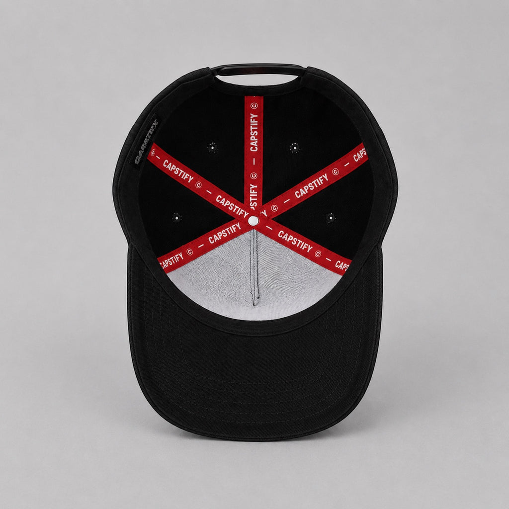 Interior view of the Capstify Skull Voltage black A-Frame baseball cap featuring a premium custom red Capstify branded inner tape, reinforced stitched panels, breathable eyelets, and a structured crown.